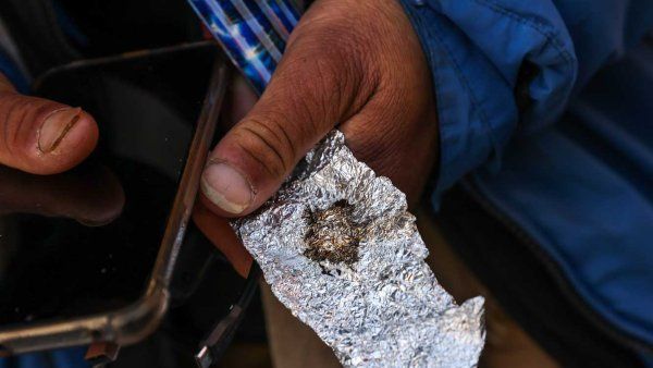 A hand holds a piece of foil with fentanyl residue.