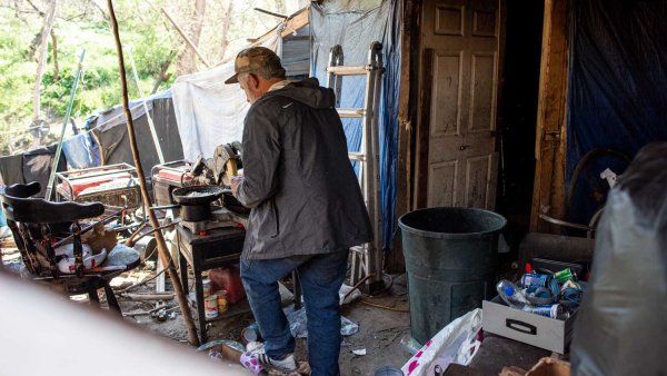 An unhoused man walkes through his encampment.