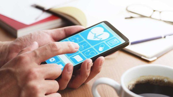 Closeup of male hands touching smartphone screen at table to use digital health applications.