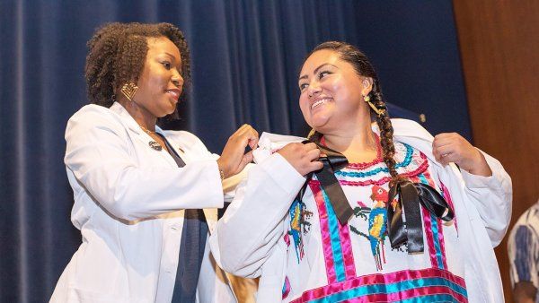 Elisa Ortega-Enriquez is receiving her white coat from Camyl Anderson