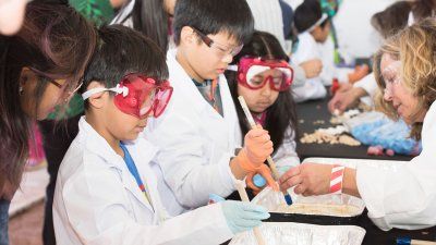 Children in lab coats and goggles conduct experiments