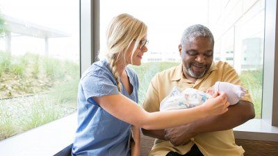 Nurse Sheena Davis and new dad Walter Johnson visit with Johnson’s 3-day-old daughter